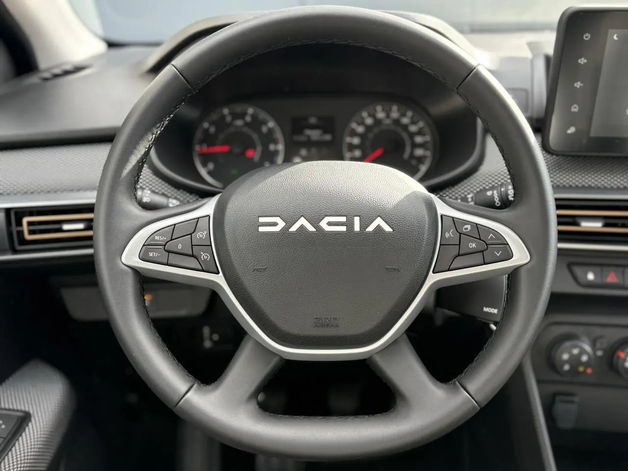 Volant noir de la Dacia Sandero Stepway 2025 vu de face, avec commandes intégrées et tableau de bord en arrière-plan.