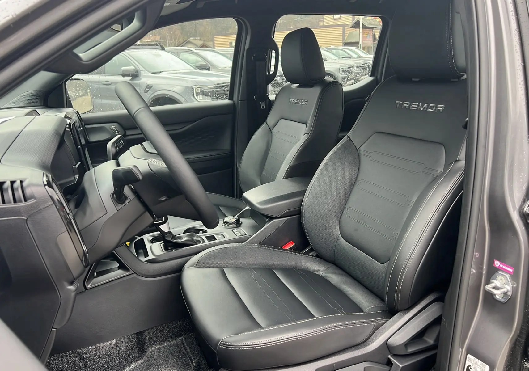 Vue intérieure côté conducteur du Ford Ranger Tremor 2025 gris carbone, sièges en cuir noir avec logo Tremor brodé.