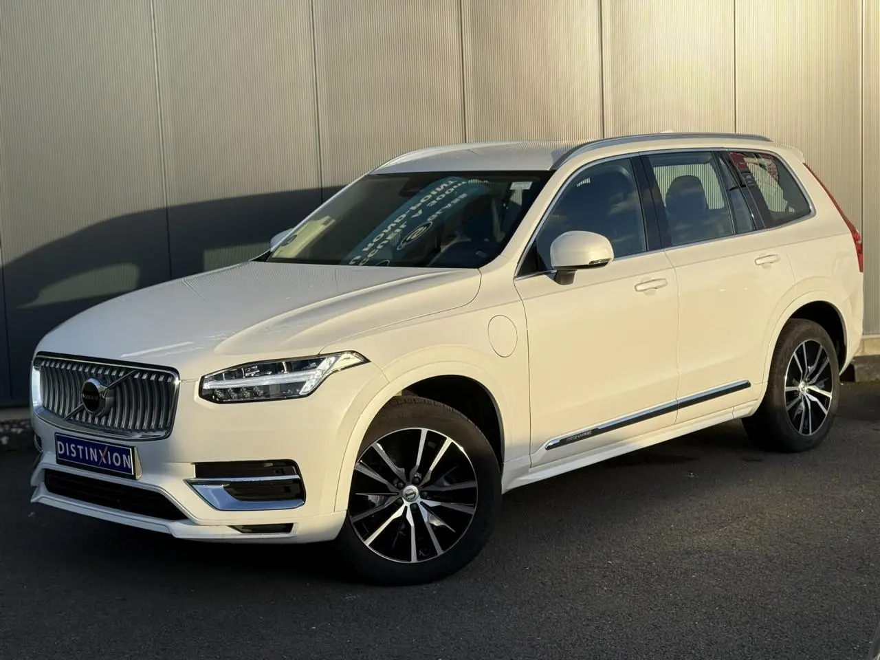 Vue 3/4 avant droite du Volvo XC90 blanc Crystal avec jantes alliage noires et chrome autour des vitres.