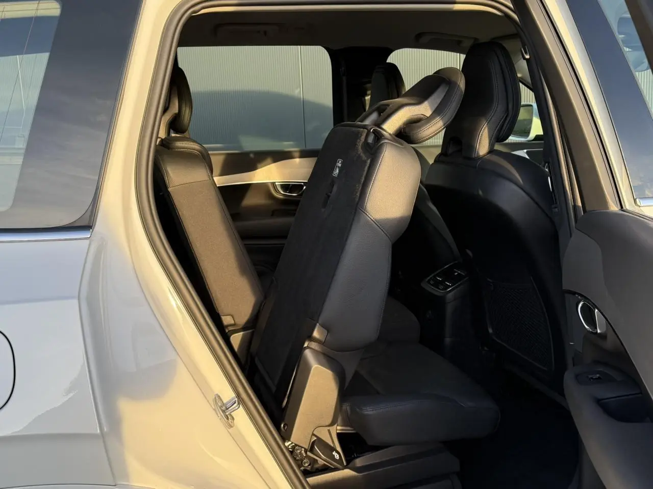 Vue intérieure côté gauche du Volvo XC90 blanc Crystal 2024 montrant les sièges arrière rabattus en partie.
