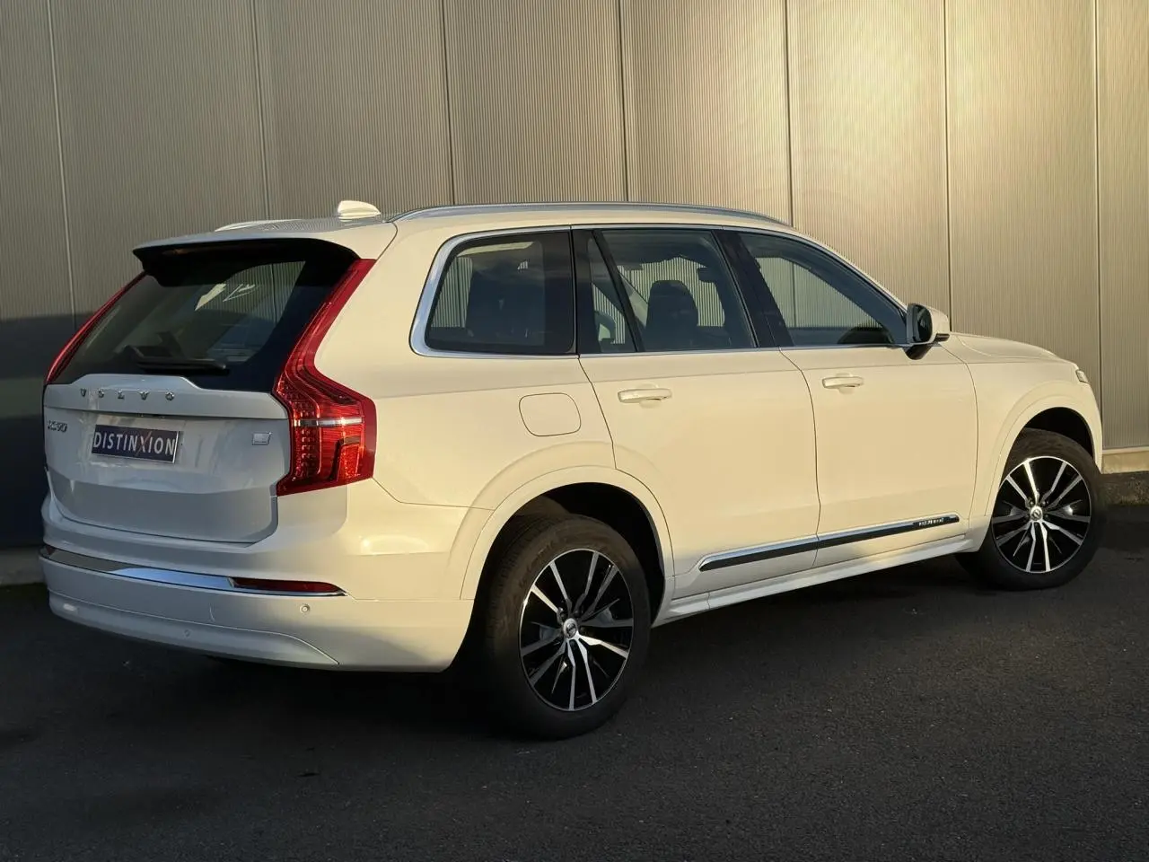 Vue 3/4 arrière droite du Volvo XC90 blanc Crystal 2024 avec jantes alliage noires et détails chromés.