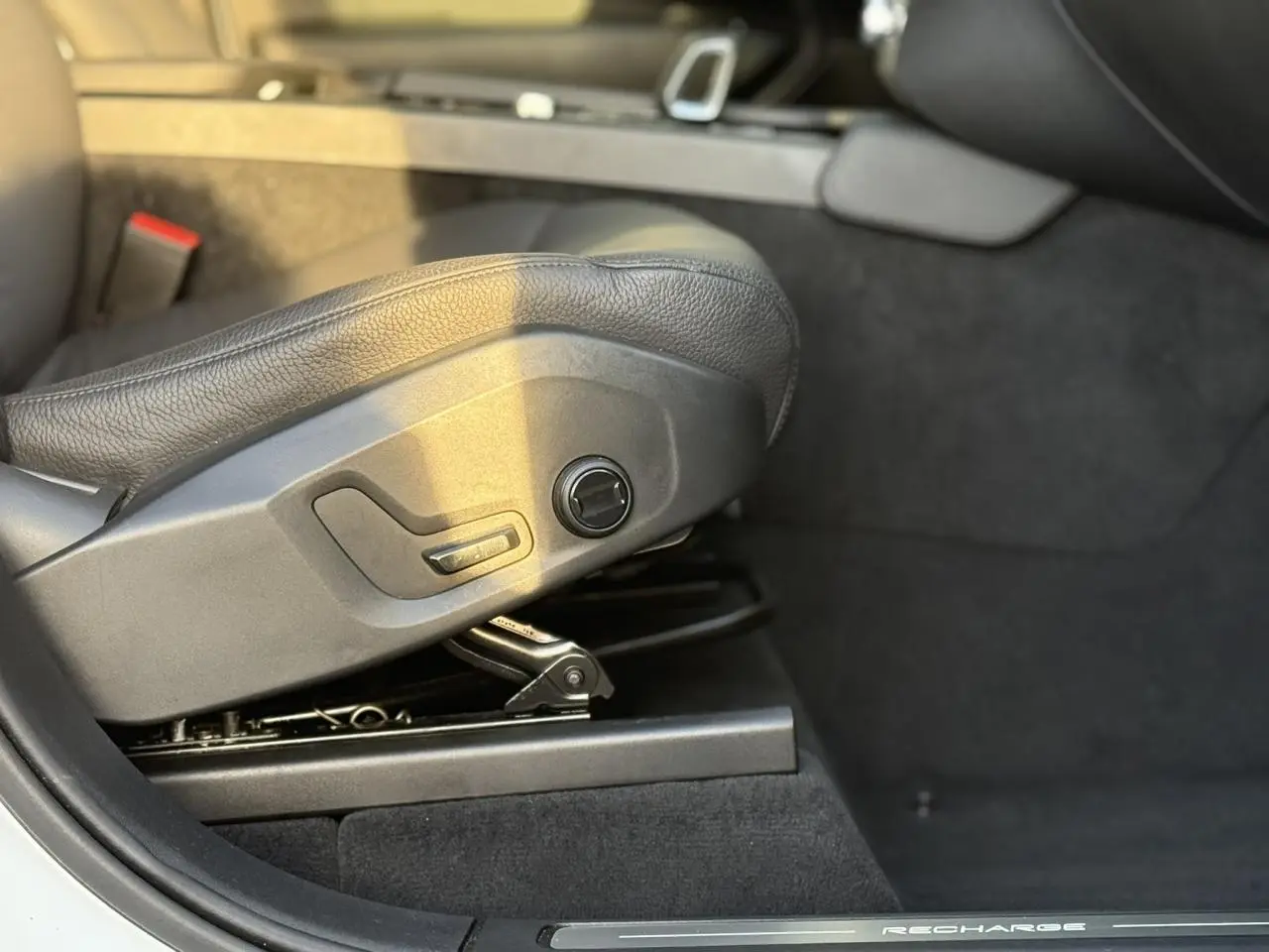 Détail du réglage électrique du siège avant en cuir noir du Volvo XC90 T8 hybride blanc, côté gauche.