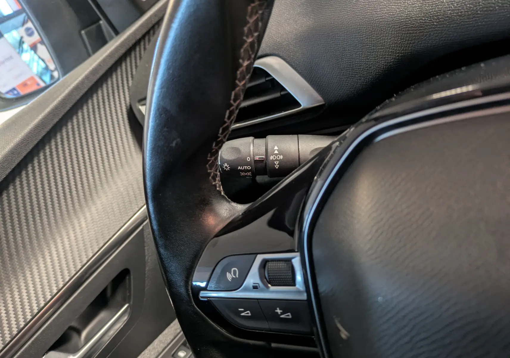 Gros plan sur le volant et la commande de régulation du volume du Peugeot 3008 gris Arthense, intérieur côté conducteur.