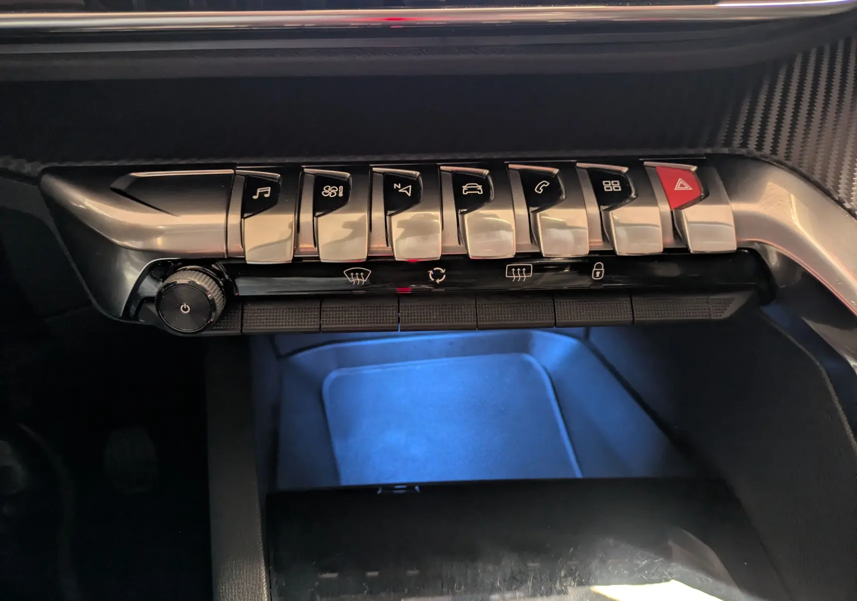 Gros plan sur la rangée de boutons chromés du tableau de bord du Peugeot 3008 gris Arthense, éclairage bleu dessous.