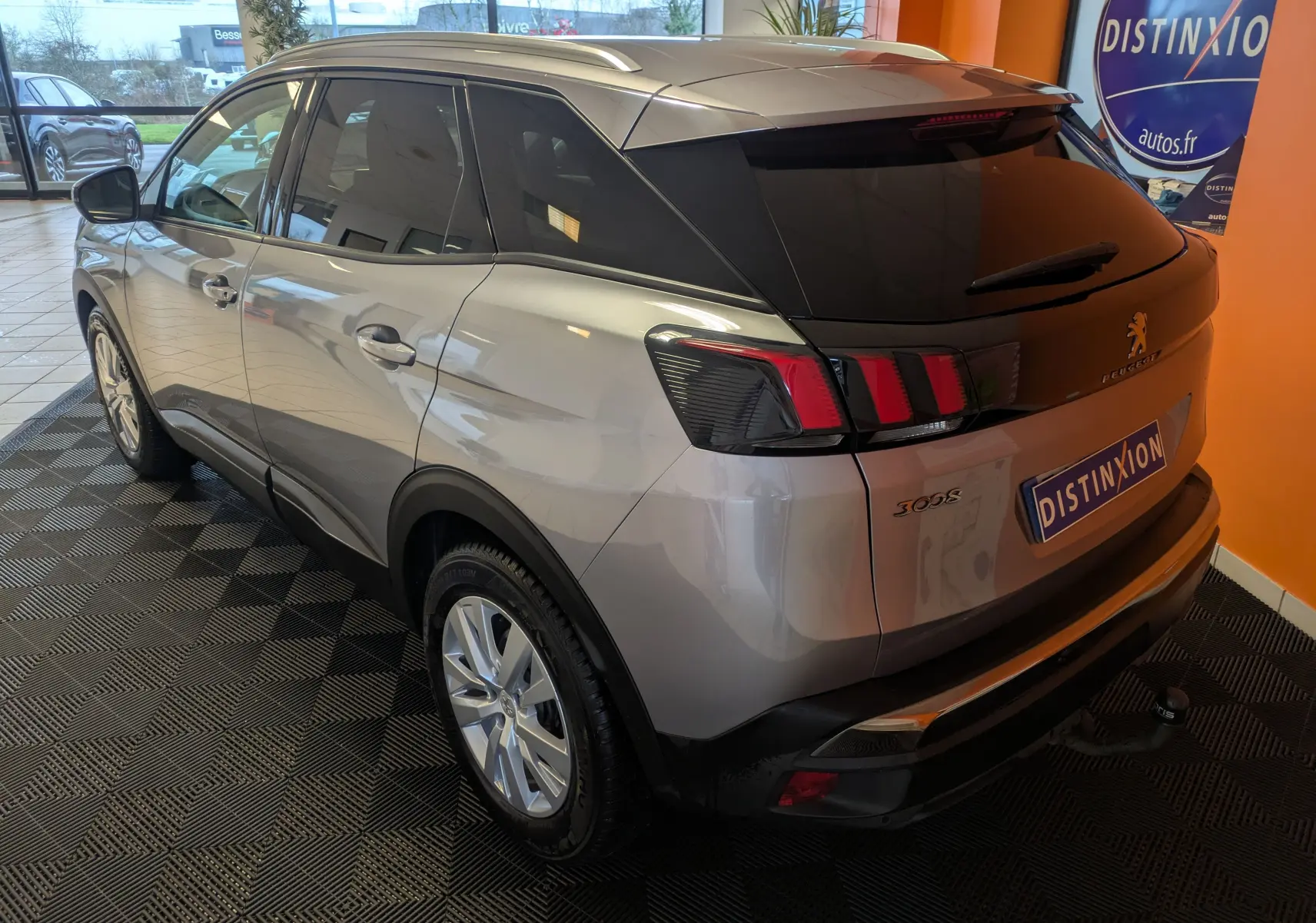 Vue 3/4 arrière droite du Peugeot 3008 gris Arthense avec vitres teintées et caméra de recul en intérieur showroom.
