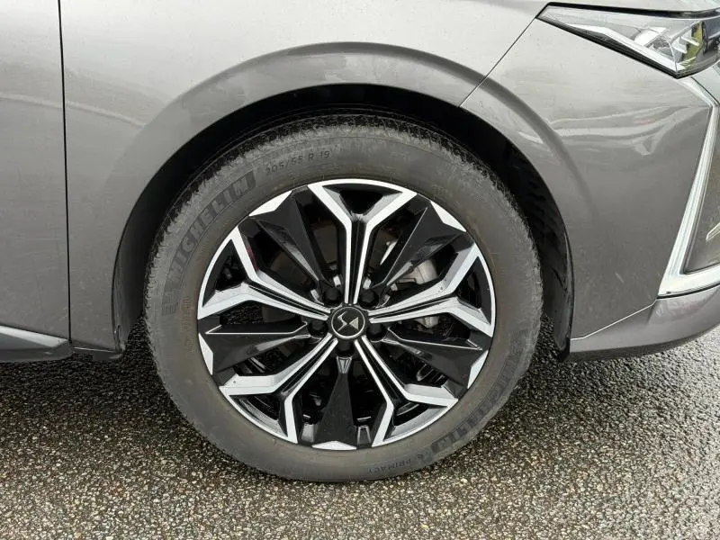 Gros plan sur la roue avant droite du DS4 2023 gris Platinium, mettant en valeur la jante alliage noire et argentée au design moderne.