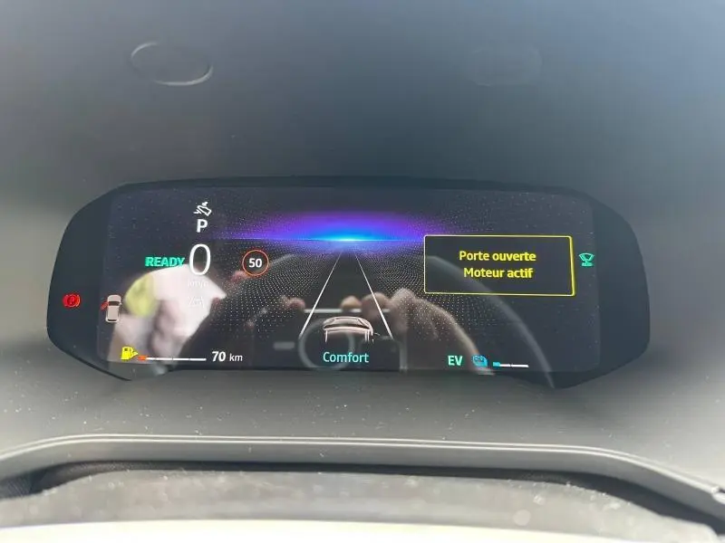 Tableau de bord numérique du Renault Captur 2026 affichant la vitesse, mode confort et alerte porte ouverte, vue frontale rapprochée.