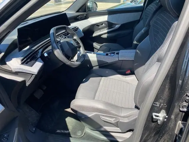 Vue intérieure côté conducteur du Peugeot 3008 noir 2024, mettant en valeur le tableau de bord numérique et les sièges gris.