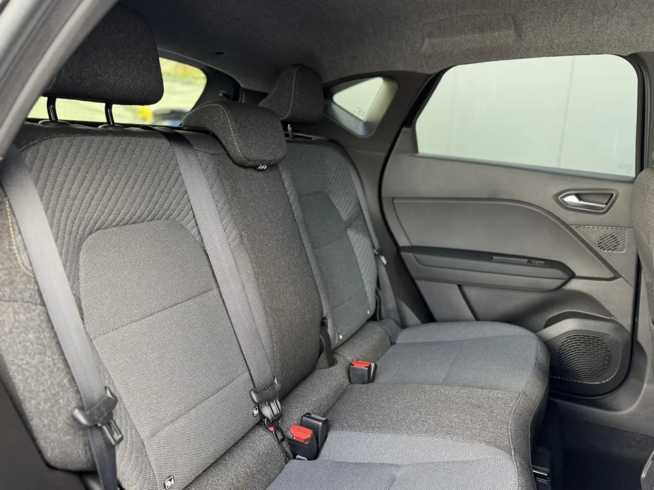 Vue latérale droite des sièges arrière gris foncé du Renault Captur 2026 avec ceinture de sécurité et garnitures de porte.