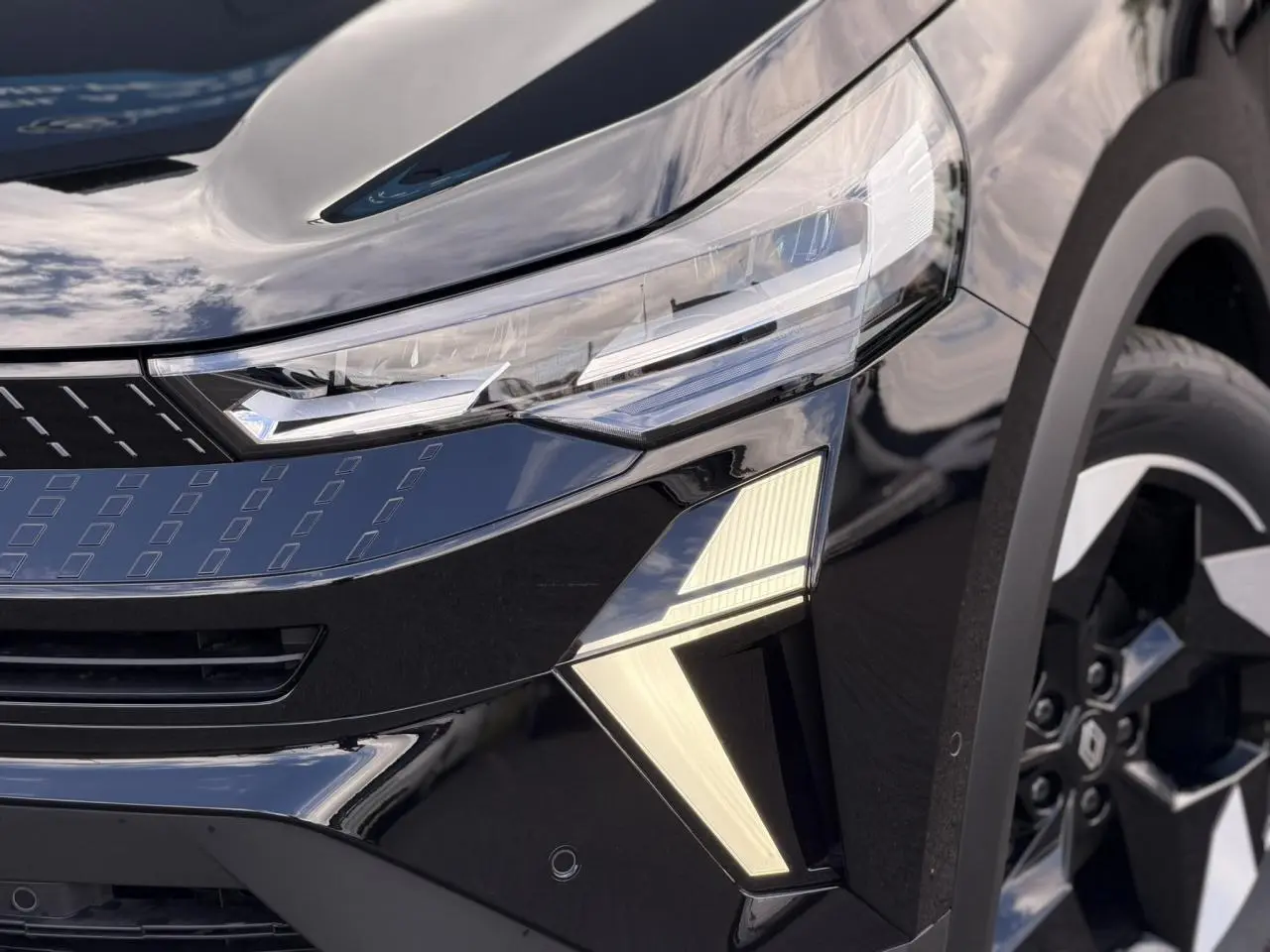 Gros plan sur l'avant droit du Renault Captur noir étoilé, mettant en valeur les phares LED et la jante aluminium 18 pouces.