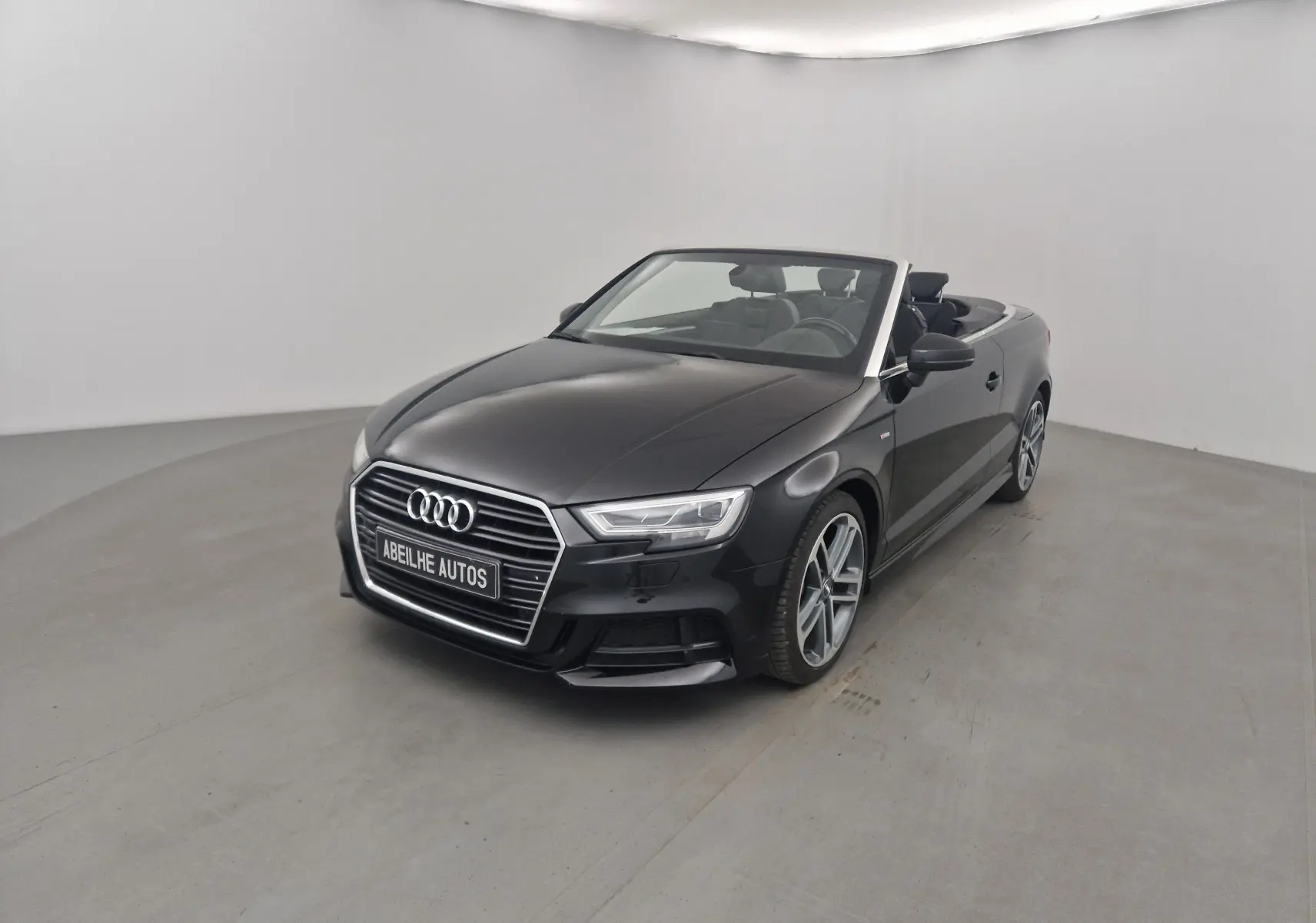 Audi A3 Cabriolet noir vue 3/4 avant avec capote ouverte, jantes alliage et intérieur visible