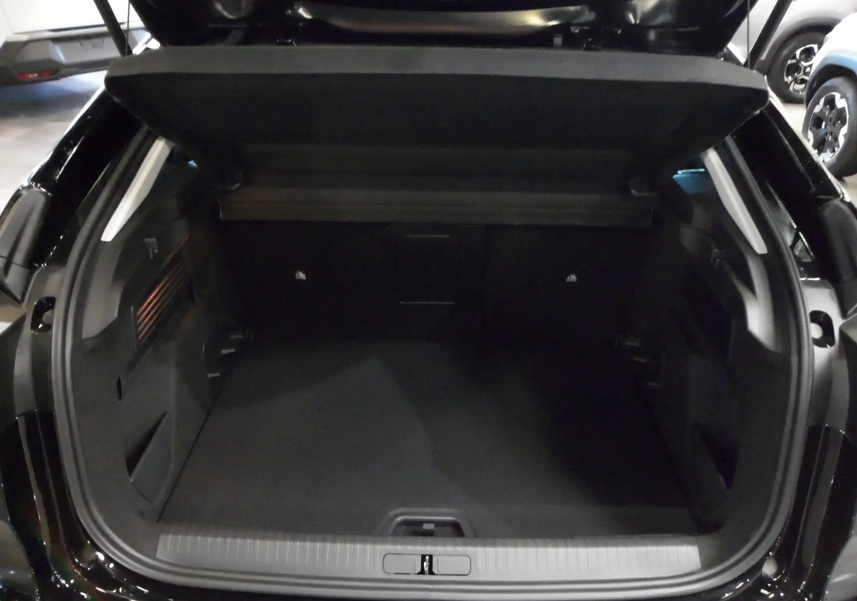 Coffre ouvert en vue arrière d'une Citroën C4 Hybride 136 e-DCS6 Max noir Perla, espace de chargement spacieux et propre.