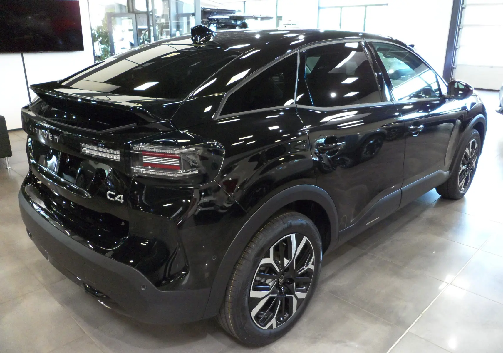 Vue 3/4 arrière droite d'une Citroën C4 Hybride 136 e-DCS6 Max noire Perla avec jantes alliage et vitres teintées.