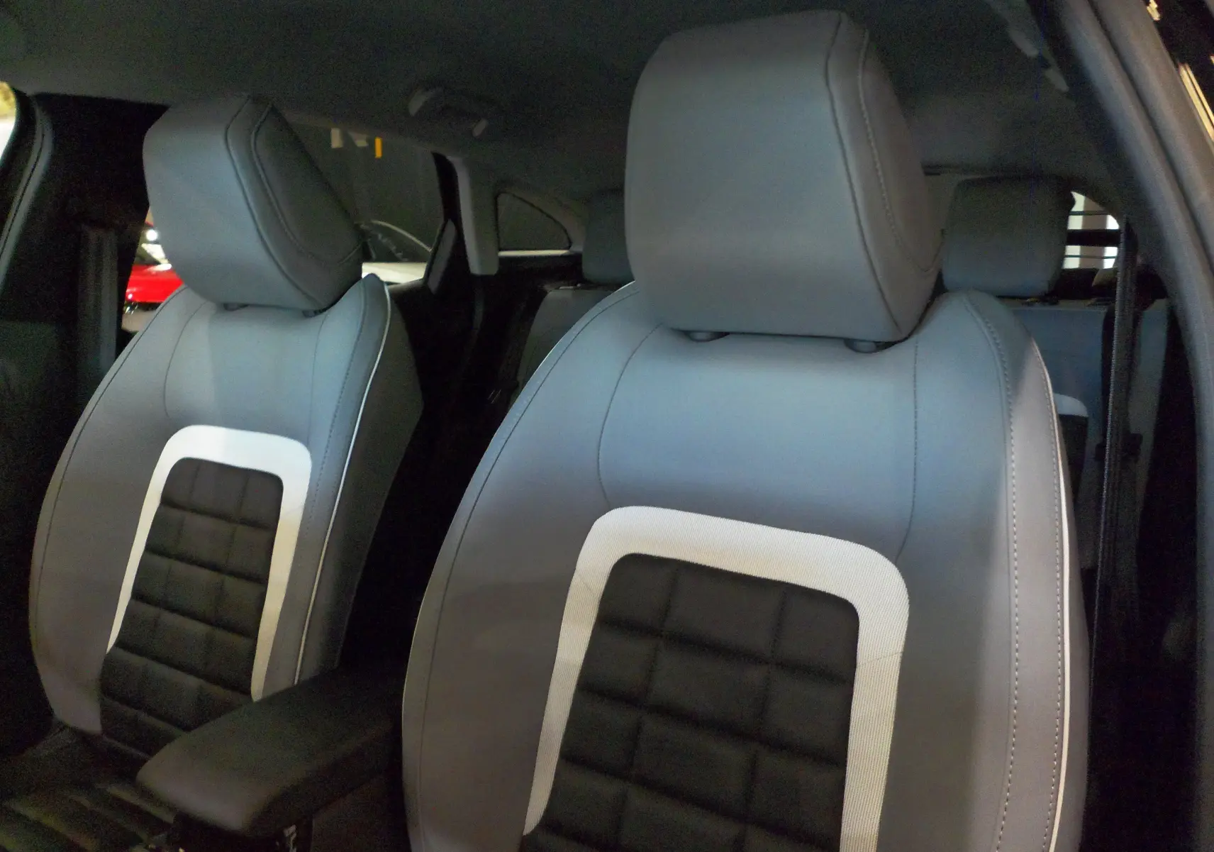 Gros plan sur les sièges avant en cuir noir et gris du Citroën C4 Hybride 136 e-DCS6 Max 2025, intérieur élégant.
