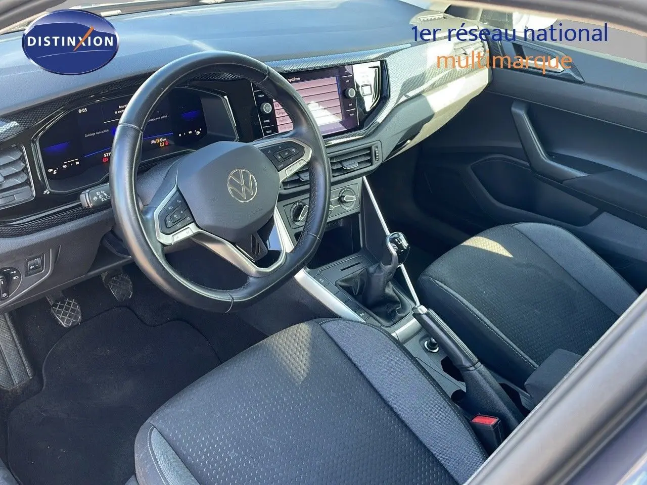 Vue intérieure du Volkswagen Taigo 1.0 TSI 110CH LIFE 2022, volant multifonction, tableau de bord numérique et sièges tissu gris.