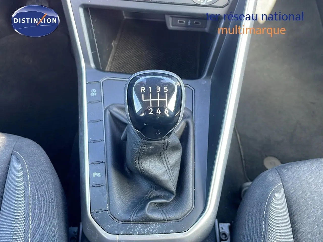 Le levier de vitesse manuel noir de la Volkswagen Taigo 1.0 TSI 110CH LIFE 2022, entouré de sièges tissu gris.