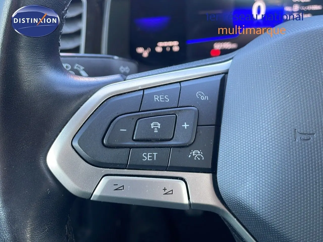 Gros plan sur les commandes au volant du Volkswagen Taigo gris cendre 2022, mettant en valeur les boutons de régulateur de vitesse.