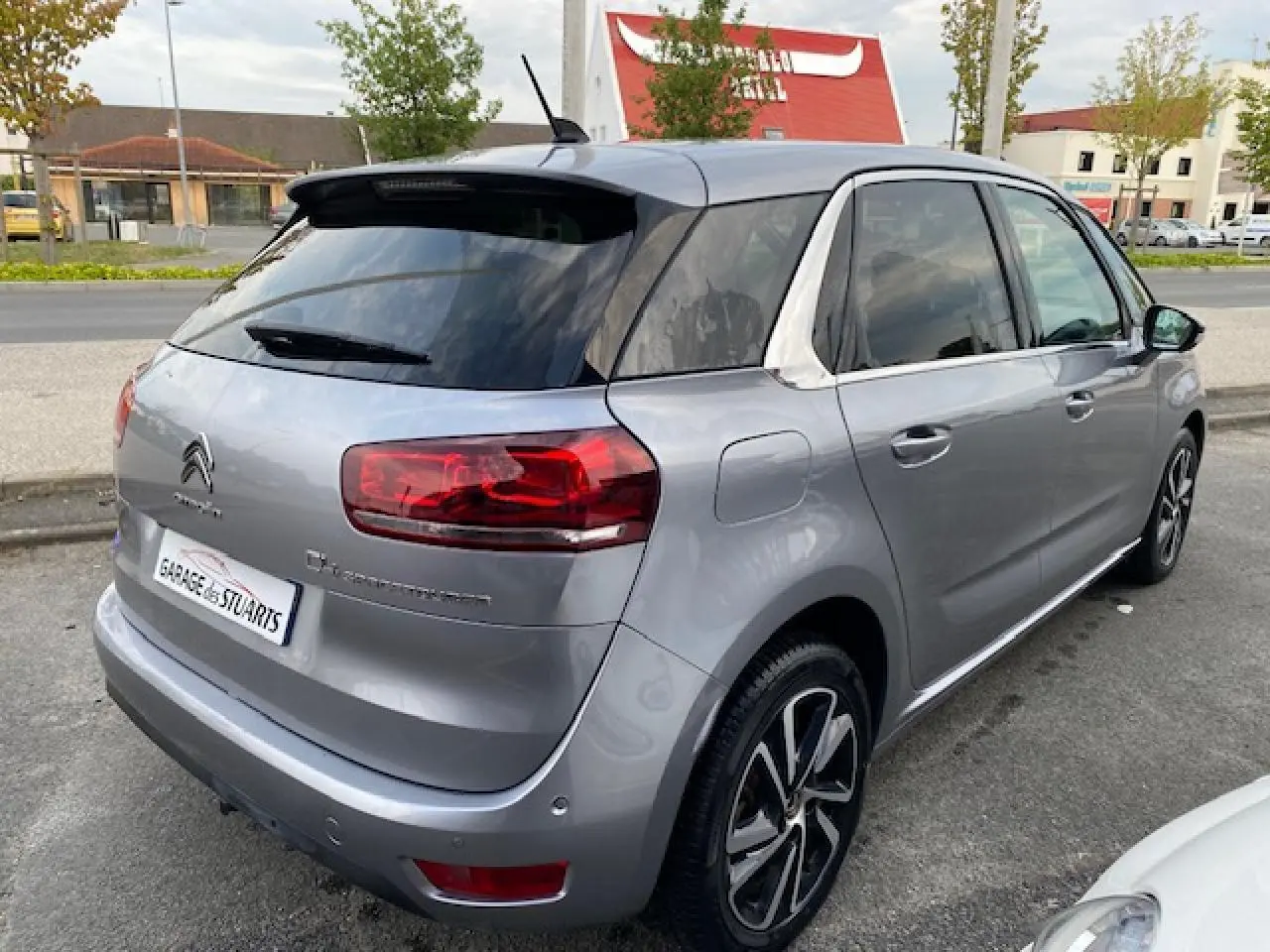 Vue 3/4 arrière droite d'une Citroën C4 Spacetourer gris Artense avec jantes alliage bi-ton et toit noir.