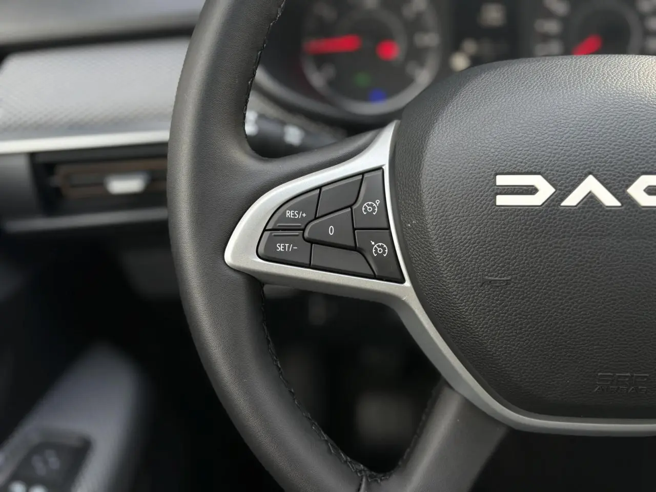 Gros plan sur le volant noir de la Dacia Sandero Stepway 2025, mettant en valeur les commandes de régulateur de vitesse à gauche.