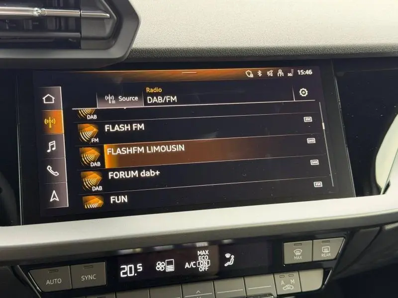 Écran tactile central de l’Audi A3 Sportback 2024 affichant les stations radio DAB/FM, avec commandes climatisation en dessous.