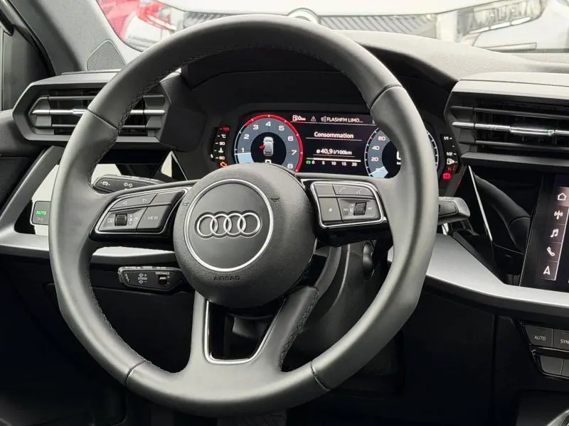 Vue intérieure centrée sur le volant cuir multifonction de l'Audi A3 Sportback 2024 avec tableau de bord numérique.