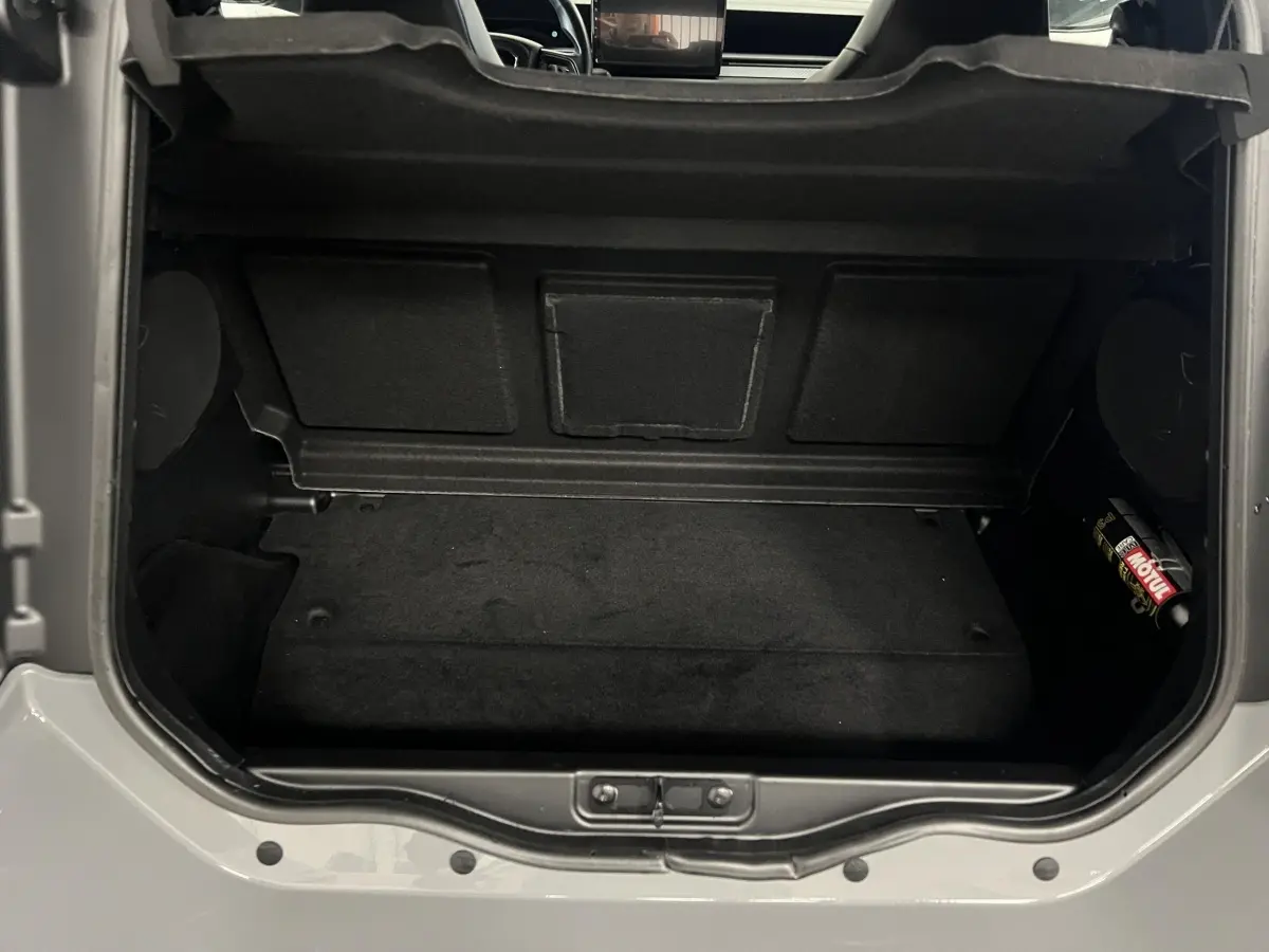 Vue plongeante sur le coffre noir ouvert d’une LIGIER JS50 bleu 2026, montrant l’espace de rangement intérieur.