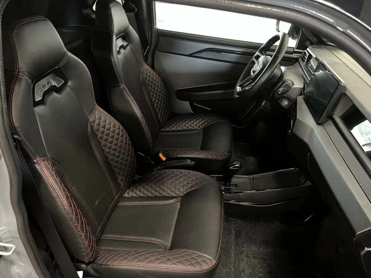 Vue intérieure côté conducteur de la Ligier JS50 0.5 REVO D+ Ultimate avec sièges noirs et surpiqûres rouges.