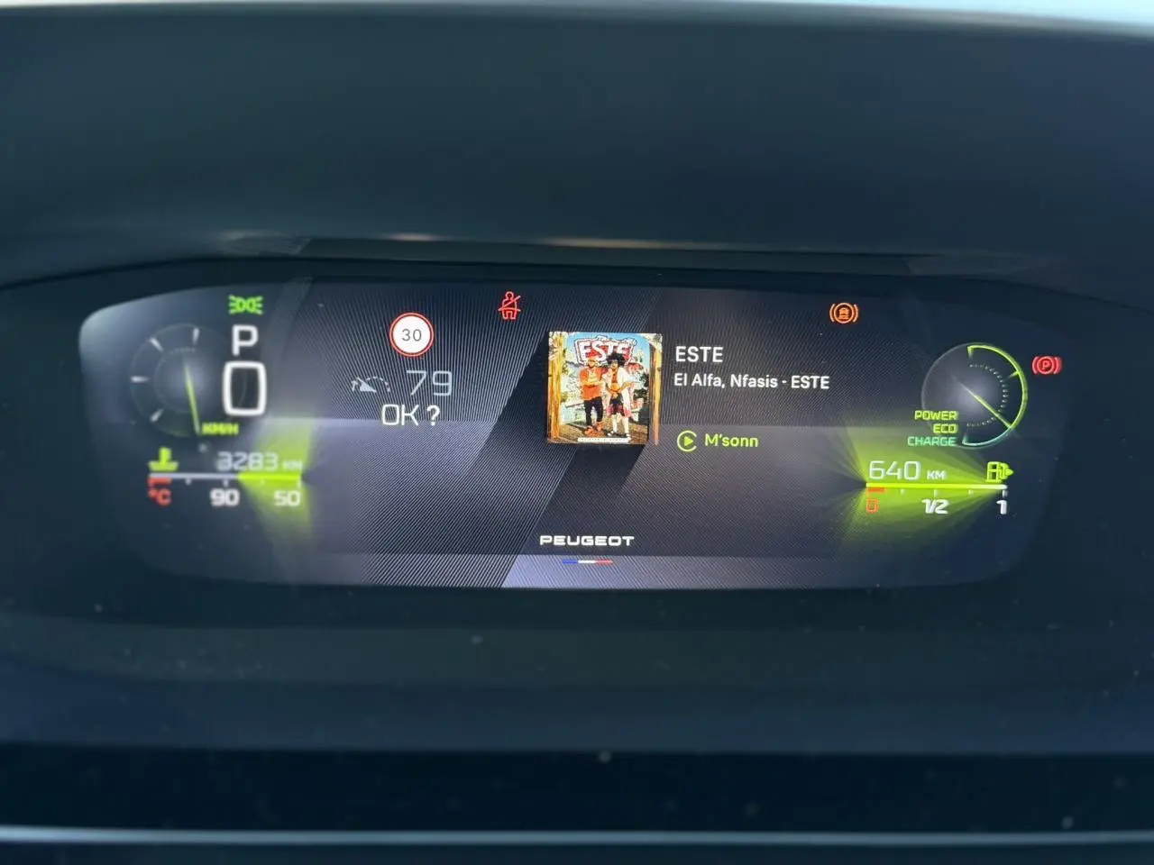 Affichage numérique du combiné Peugeot 408 Hybrid 2025 avec informations de conduite et musique en cours.