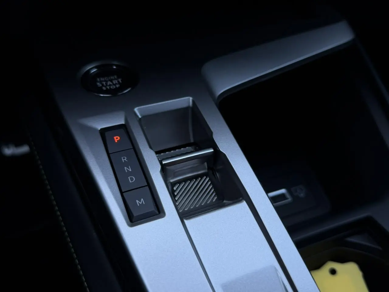 Gros plan sur la console centrale grise avec levier de vitesses automatique et bouton start/stop du Peugeot 408 Hybrid 145 GT.