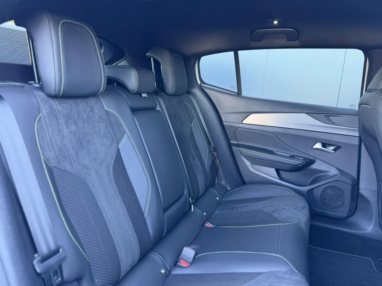 Vue latérale droite de la banquette arrière en alcantara noir avec surpiqûres vertes du Peugeot 408 Hybrid 145 GT 2025.