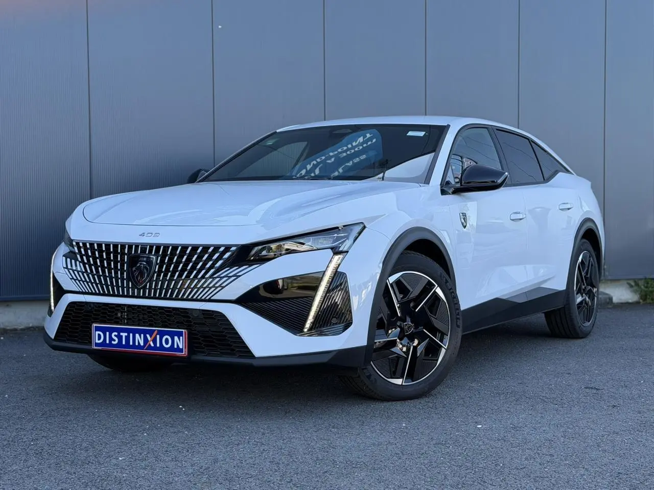 Peugeot 408 Hybrid blanc Okenite vue 3/4 avant droit, avec calandre distinctive et jantes alliage noires.
