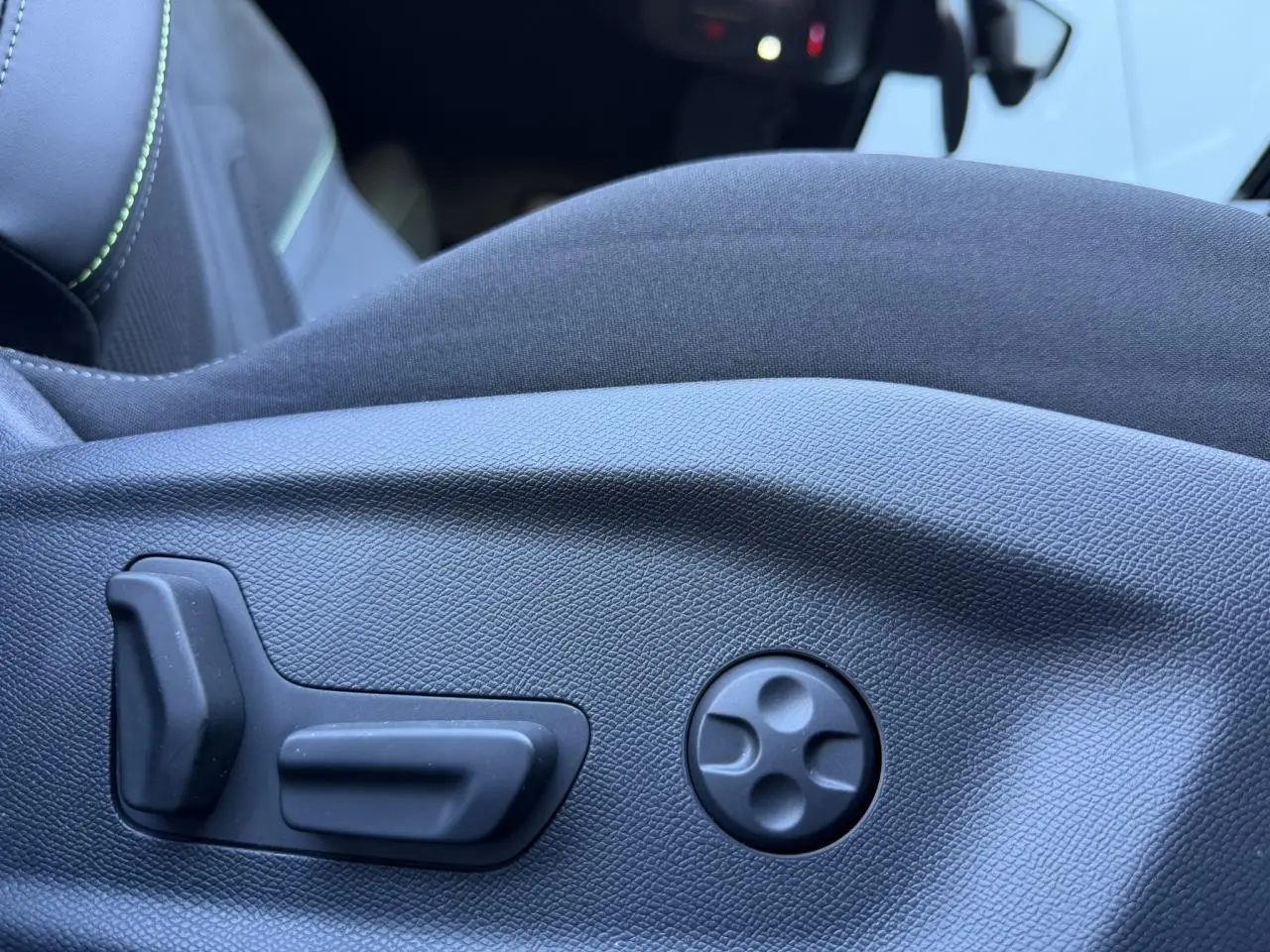 Gros plan sur les commandes électriques de réglage du siège conducteur en alcantara noir du Peugeot 408 Hybrid blanc.