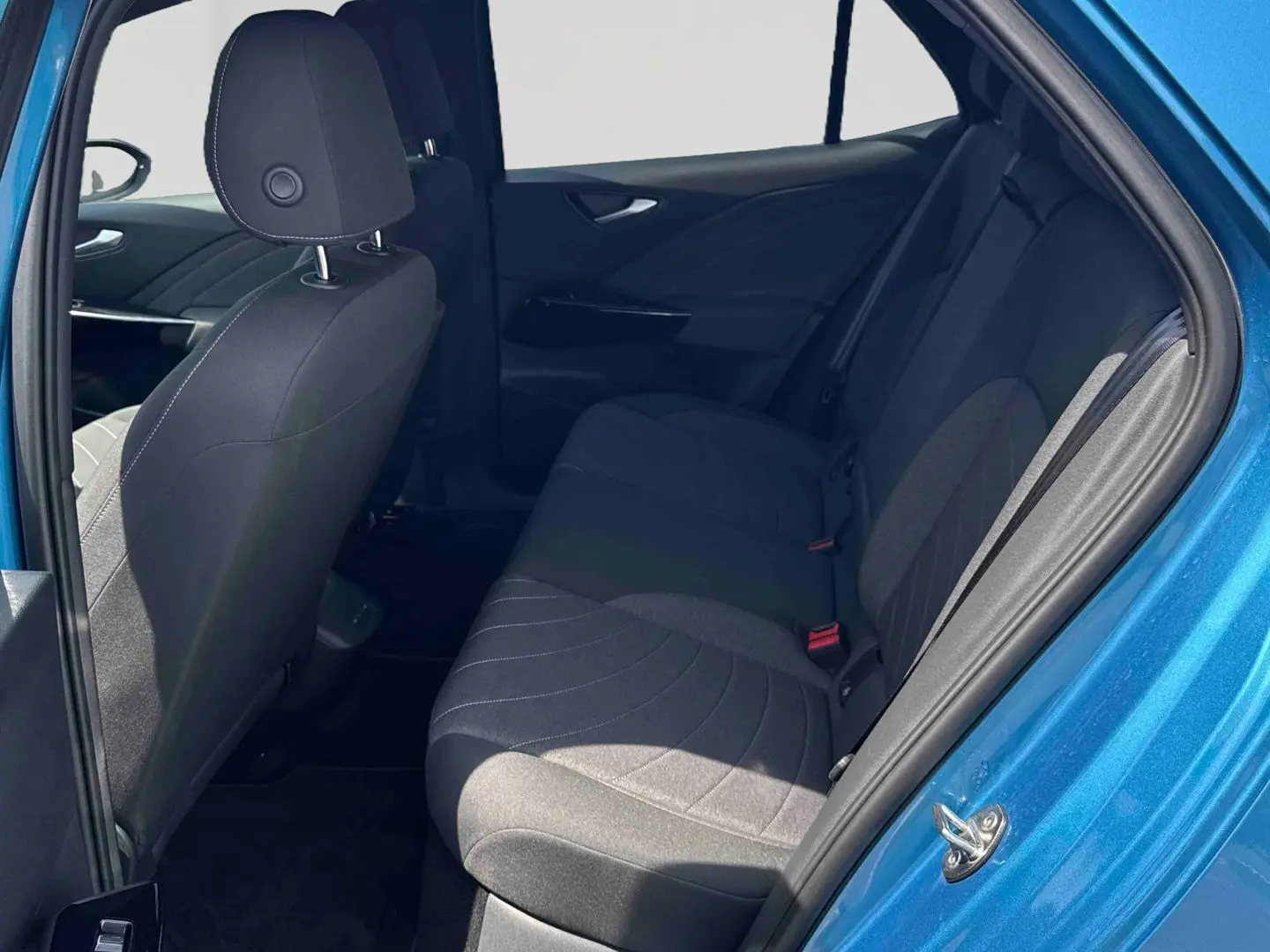 Vue intérieure côté droit sur la banquette arrière et la portière bleue d'un Volkswagen ID.3 2025 électrique.