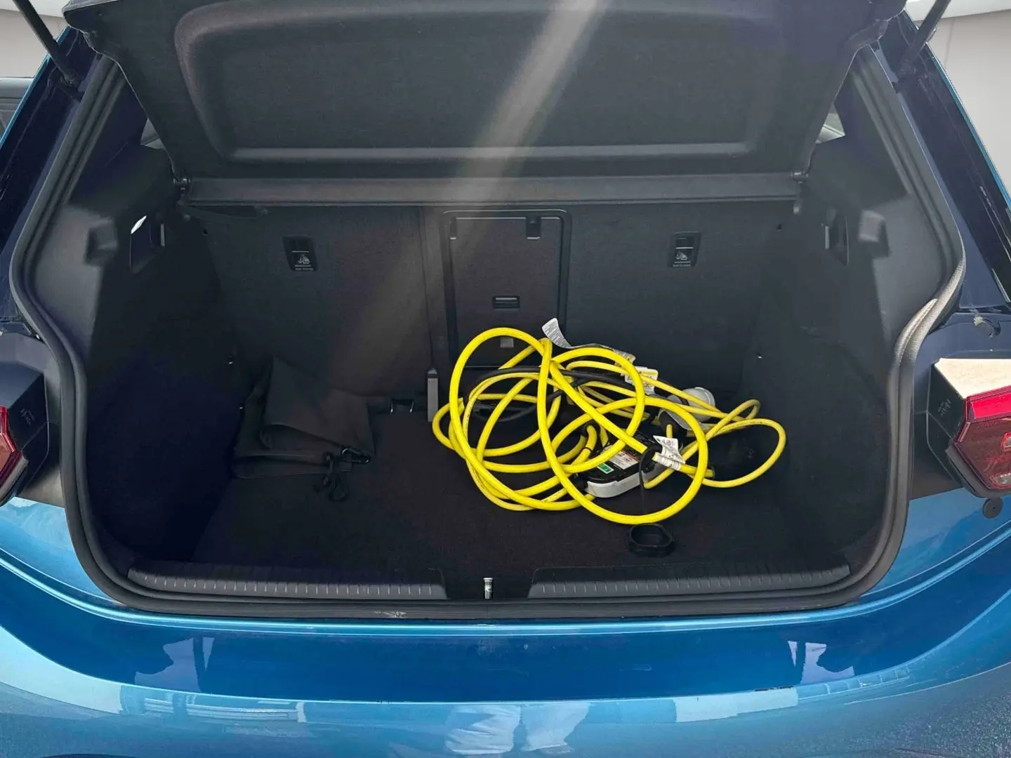 Coffre ouvert d'une Volkswagen ID.3 204 ch Pro S bleu, avec câble de recharge électrique jaune visible à l'intérieur.
