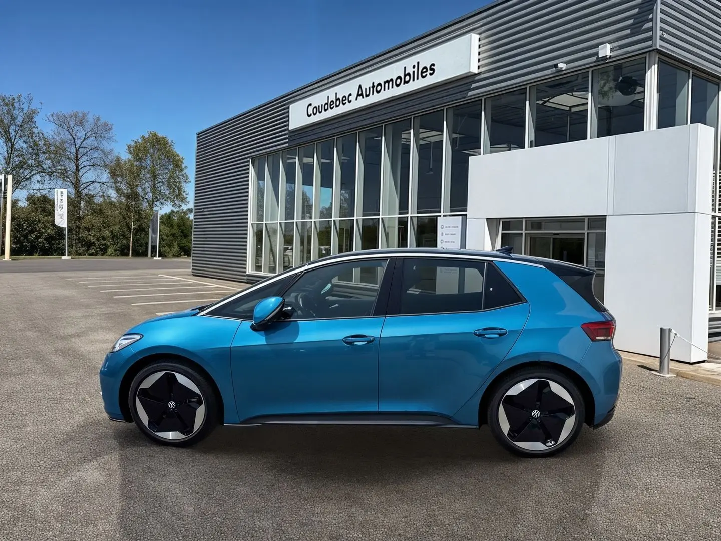 Vue de profil côté gauche d'une Volkswagen ID.3 204 ch Pro S 77 kWh bleu métallisé avec jantes 20 pouces devant un concessionnaire.