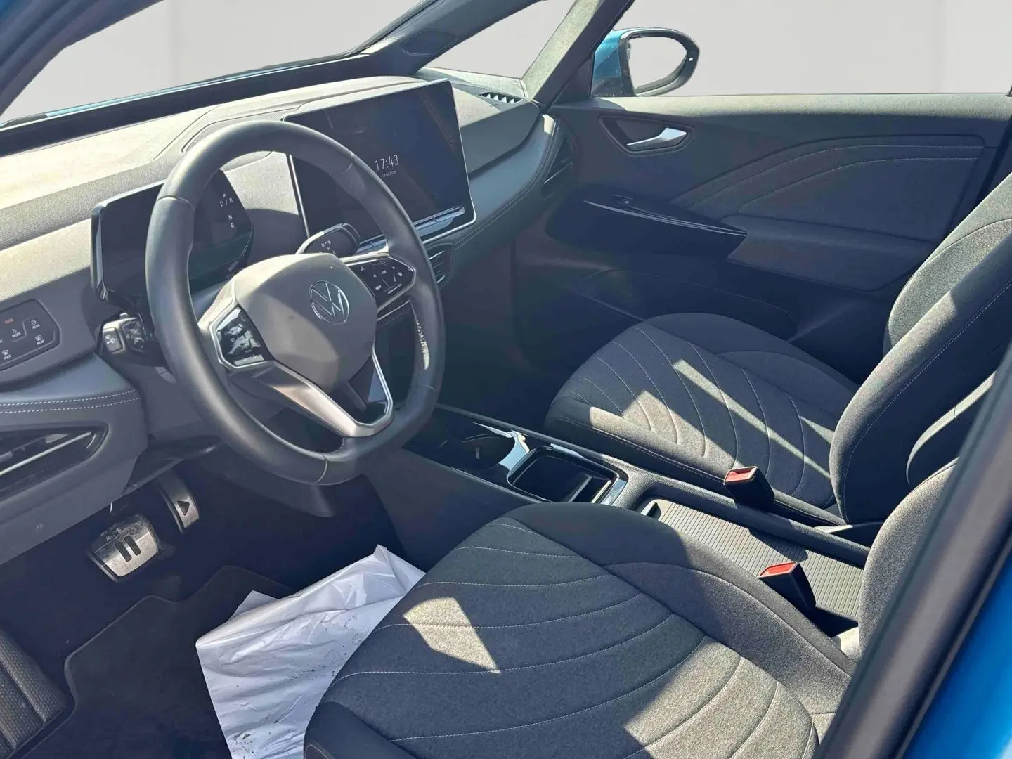Vue intérieure côté conducteur du Volkswagen ID.3 bleu 2025, avec volant multifonction et sièges tissu gris.