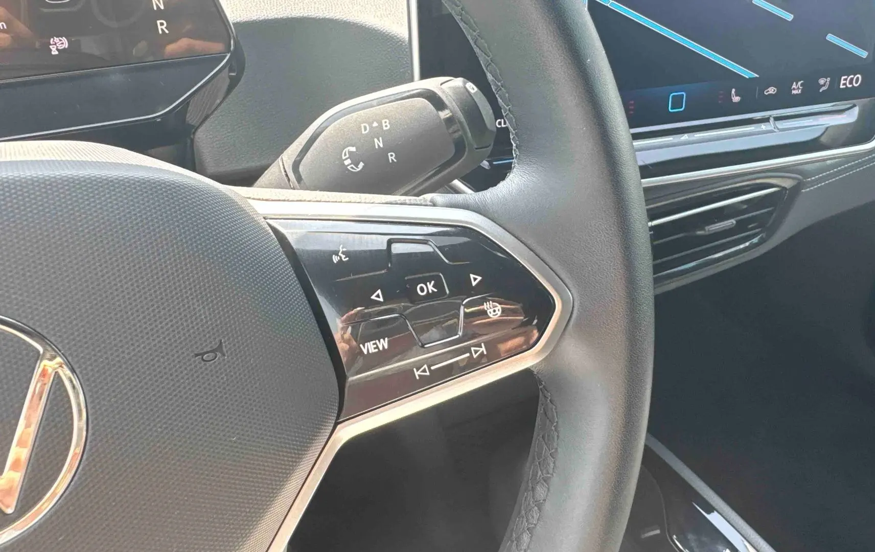 Gros plan sur le volant multifonction noir du Volkswagen ID.3 2025 avec commandes tactiles et écran tactile central visible.