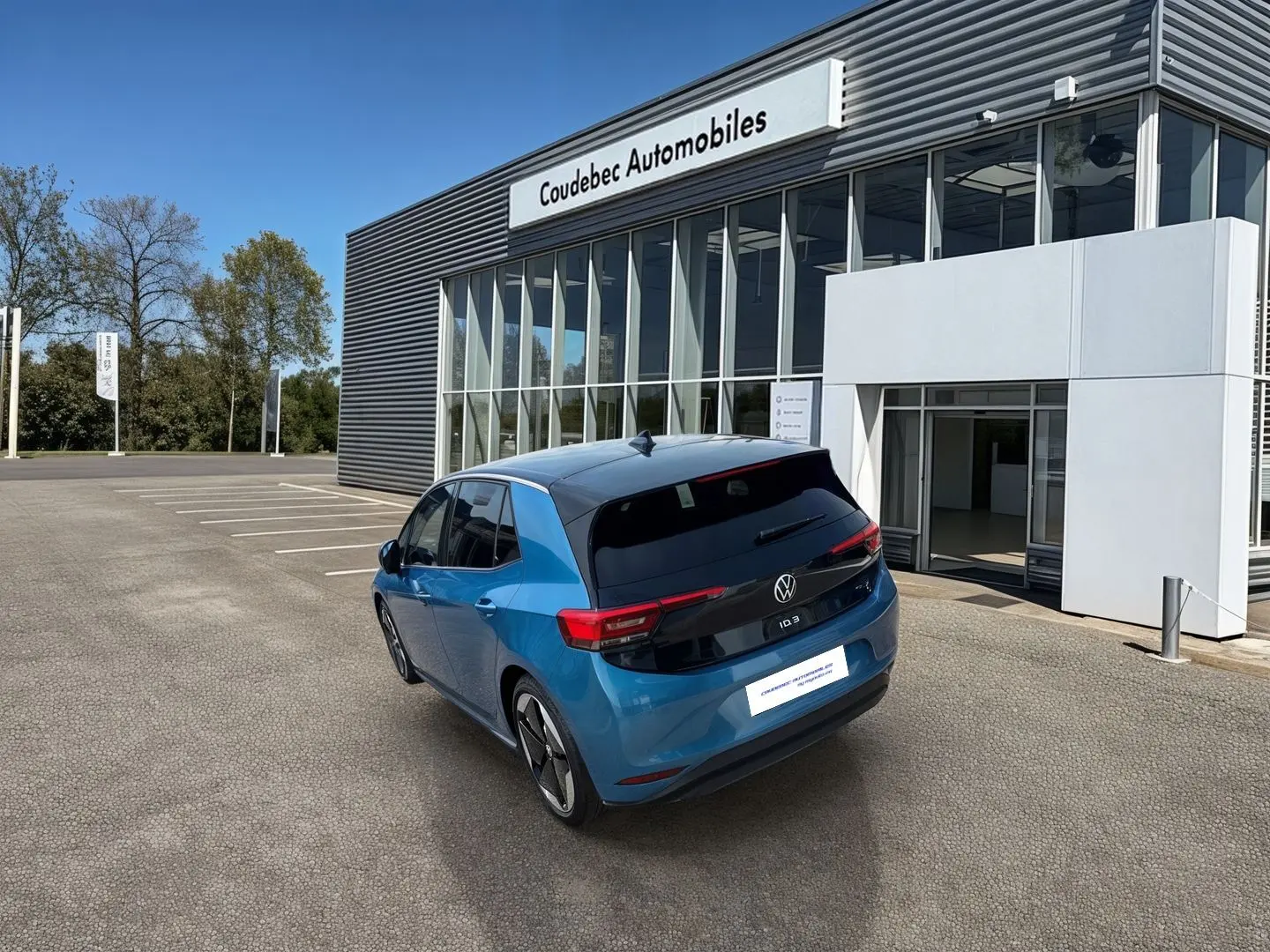 Vue 3/4 arrière droite d'une Volkswagen ID.3 204 ch Pro S 77 kWh bleu métallisé avec toit noir devant un concessionnaire.