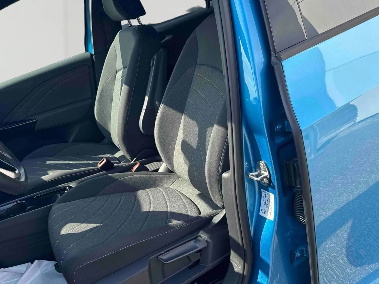 Vue intérieure côté conducteur du Volkswagen ID.3 204 ch Pro S 77 kWh bleu, avec sièges avant en tissu gris.