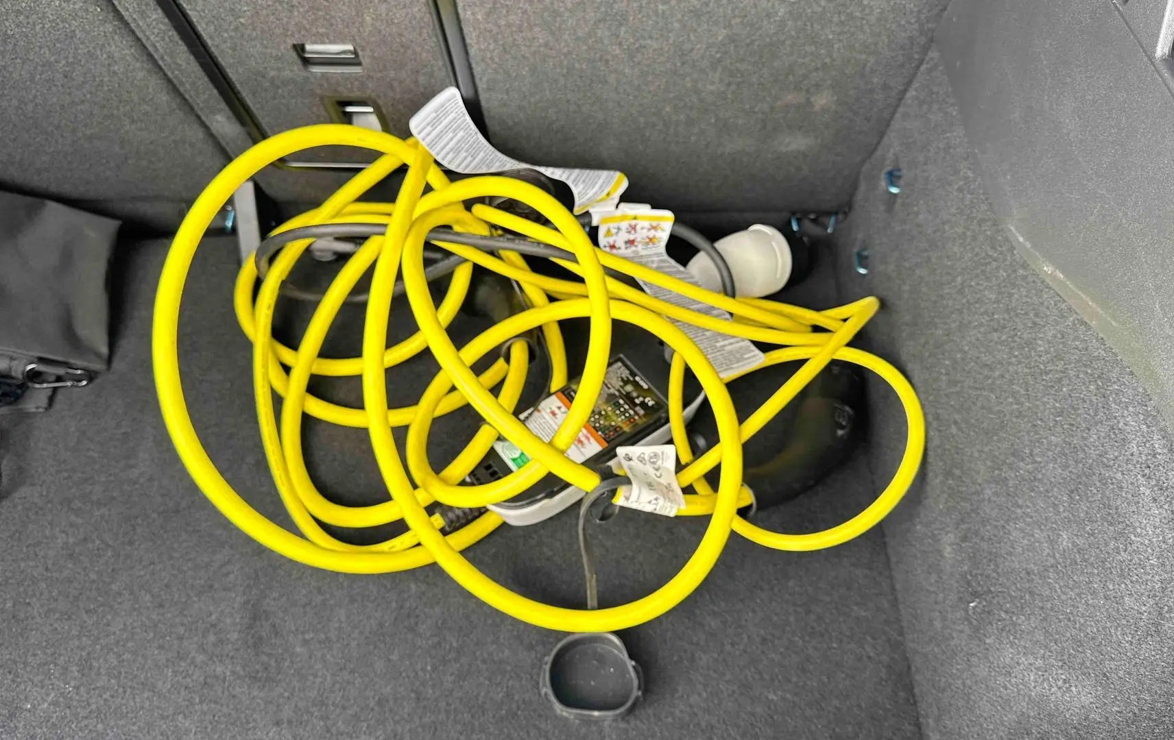 Câble de recharge électrique jaune enroulé dans le coffre d’un Volkswagen ID.3 2025 bleu.