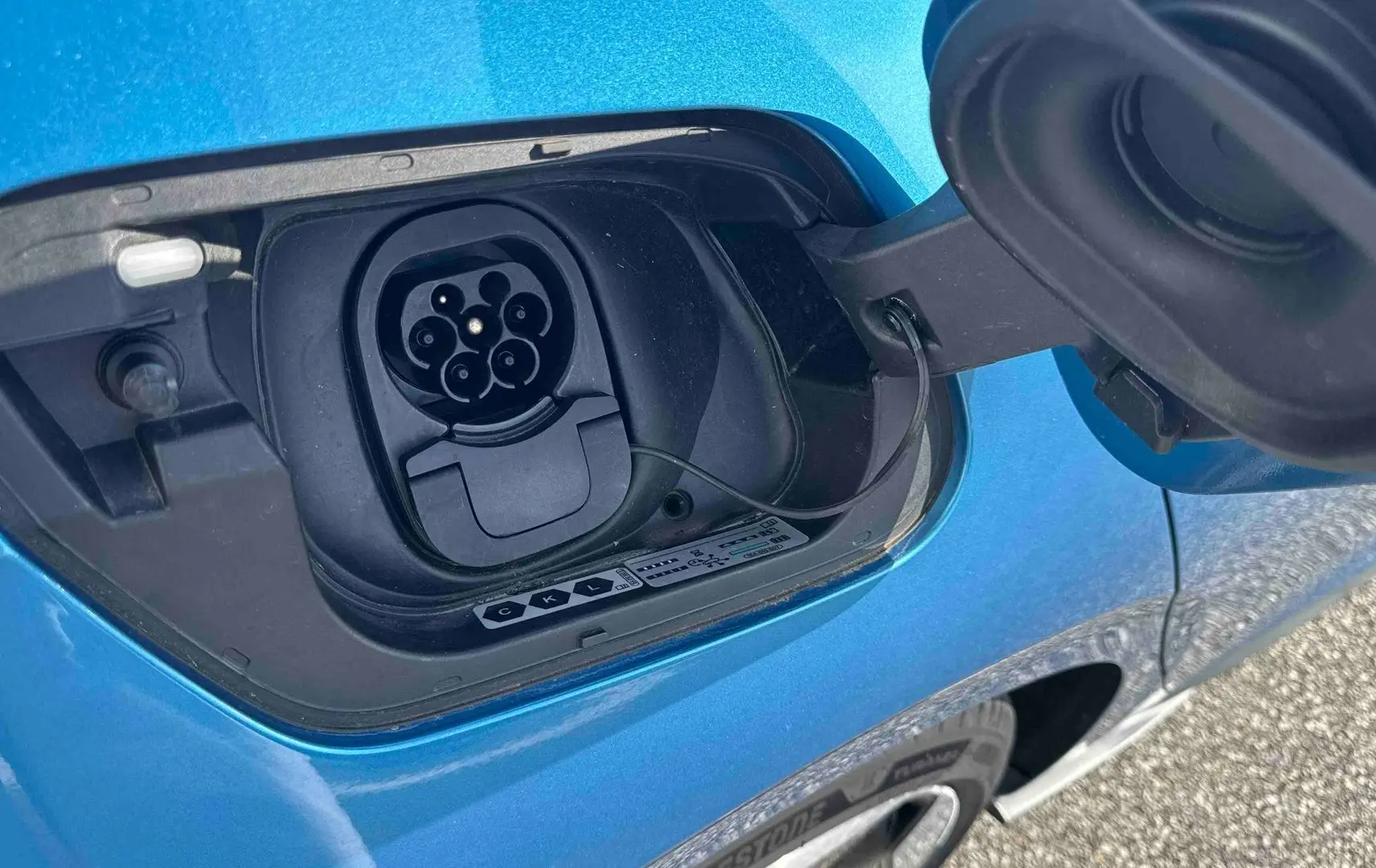 Prise de recharge électrique ouverte sur le côté gauche d'une Volkswagen ID.3 bleue métallisée.