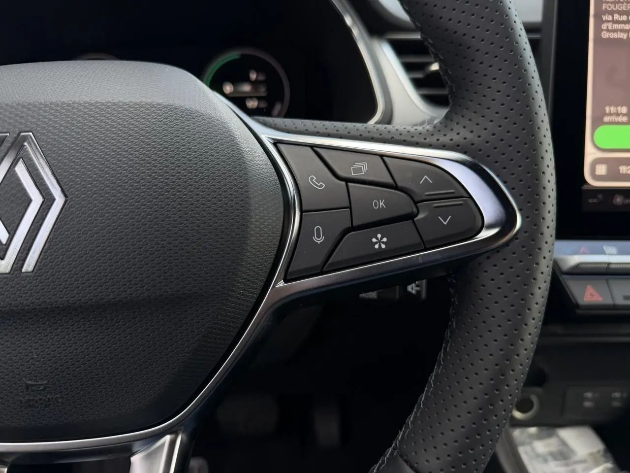 Gros plan sur le volant en cuir perforé noir du Renault Captur 2026 avec commandes multifonctions et logo central chromé.
