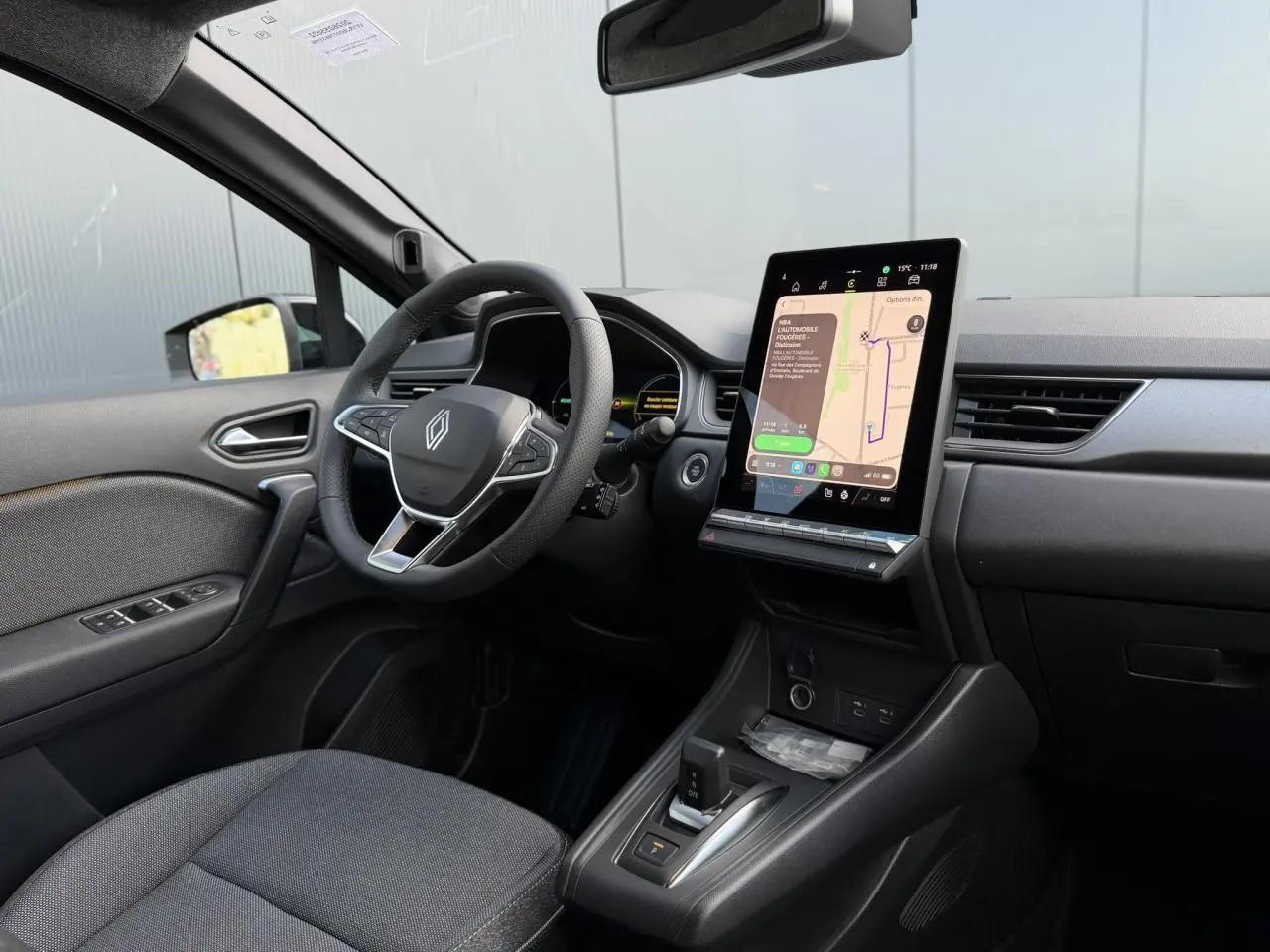 Vue intérieure côté conducteur du Renault Captur 2026 avec tableau de bord noir et écran tactile central vertical.