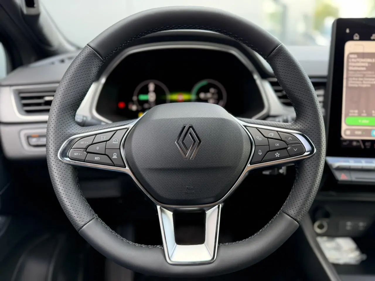 Vue rapprochée du volant noir perforé du Renault Captur 2026 avec commandes intégrées et tableau de bord numérique flou.