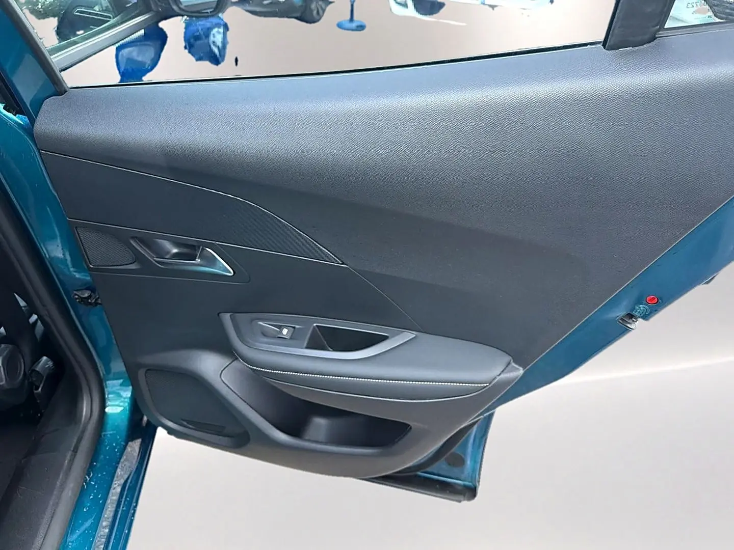 Vue rapprochée de la porte arrière gauche bleu obsession du Peugeot 2008 1.2 hybrid 145 allure e-dcs6 avec garniture noire.