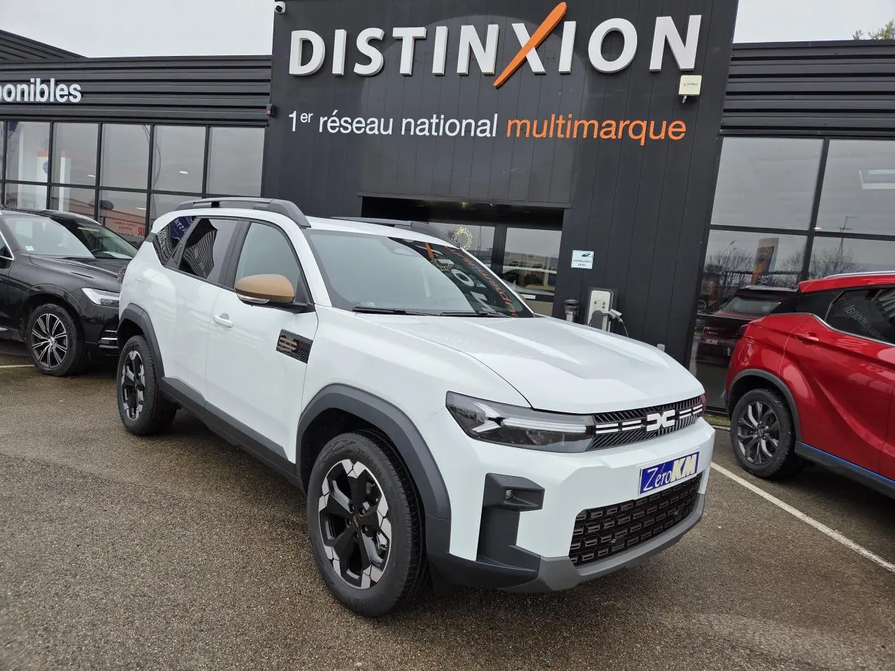 Dacia Bigster blanc glacier en 3/4 avant droit avec rétroviseurs brun cuivré et jantes noires semi-diamantées.