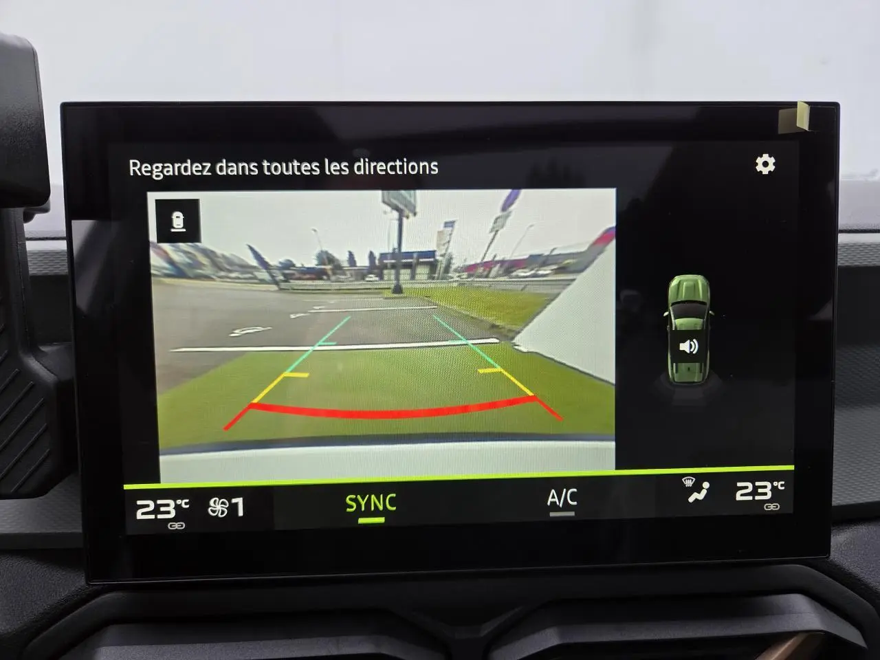 Écran tactile intérieur montrant la caméra de recul du Dacia Bigster blanc glacier avec lignes de guidage colorées.