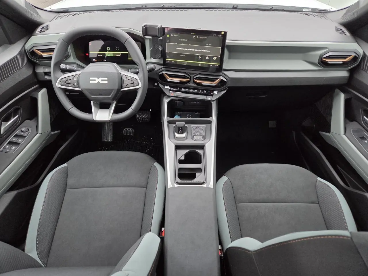 Vue intérieure avant du Dacia Bigster 2025 avec tableau de bord moderne, écran tactile et sellerie gris foncé.