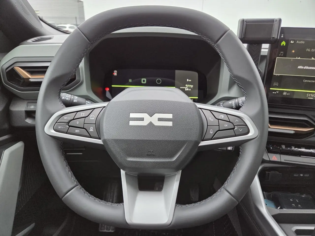 Vue frontale du volant noir et gris du Dacia Bigster 2025 avec commandes intégrées et tableau de bord numérique.