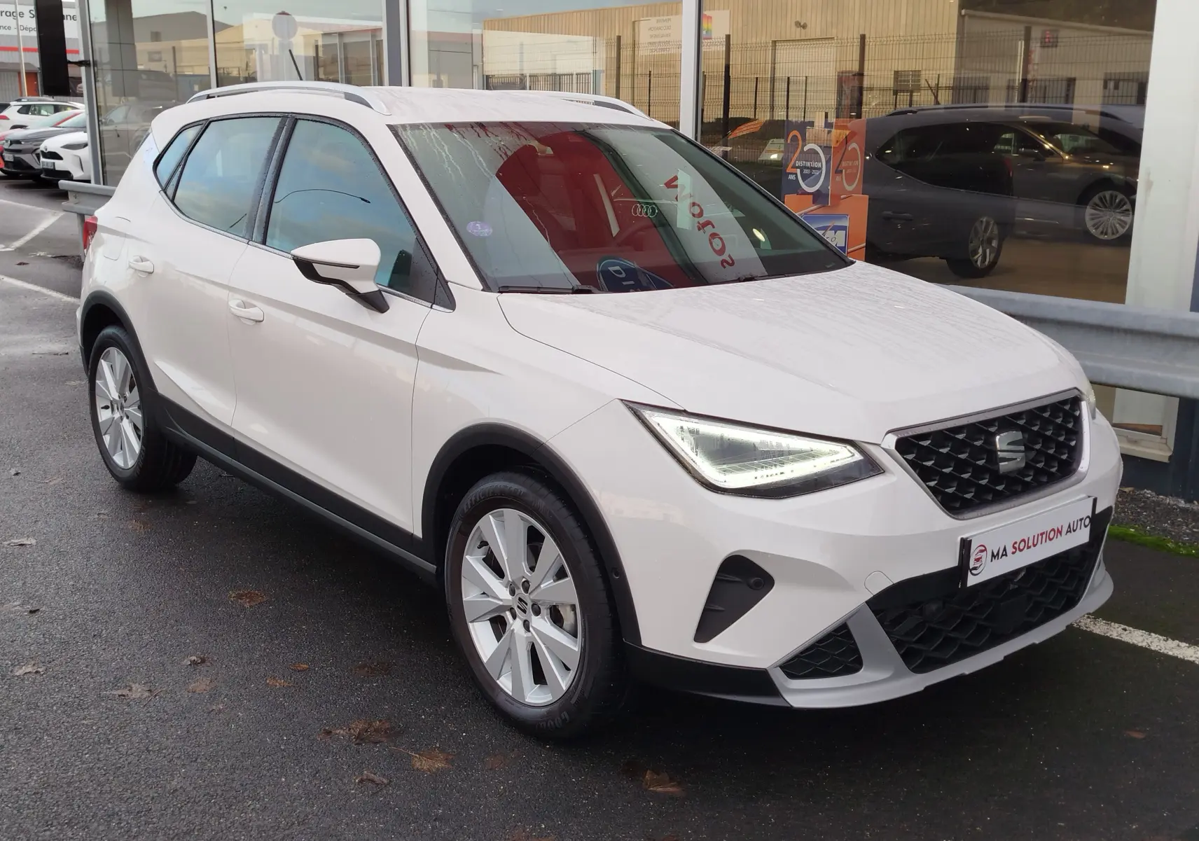 SEAT Arona blanc candy vue 3/4 avant droit, avec phares LED allumés et jantes alliage visibles.